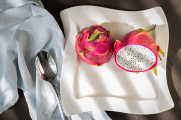 A Dragon Fruit (Hylocereus Undatus) on white plate with a metal spoon.
