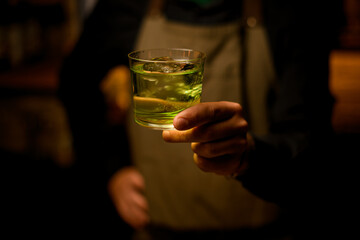 selective focus of glass with drink which hand of a male bartender holds