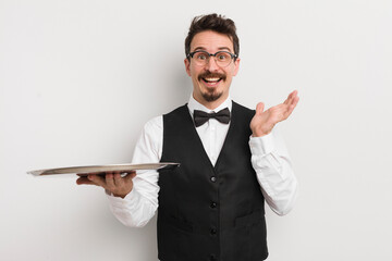 young handsome man feeling happy and astonished at something unbelievable. waiter and tray concept