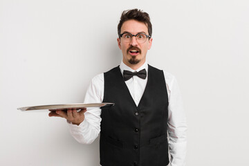 young handsome man looking very shocked or surprised. waiter and tray concept - obrazy, fototapety, plakaty