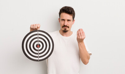 young handsome man making capice or money gesture, telling you to pay. dart target concept