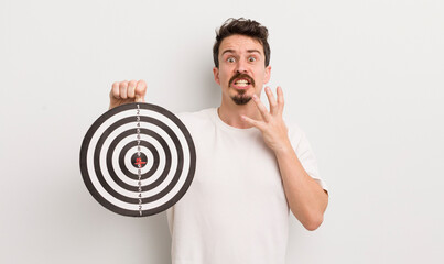 young handsome man looking desperate, frustrated and stressed. dart target concept