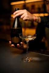 beautiful wine glass with drink on bar. Hand of a man bartender with a bottle in the background