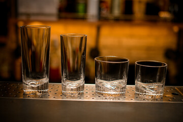 front view of a group of clear empty cocktail glasses on the bar counter.