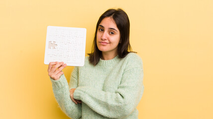 young hispanic woman shrugging, feeling confused and uncertain. puzzle concept