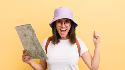 young hispanic woman shouting aggressively with an angry expression. tourist and map concept