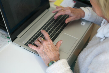 Elderly woman using the laptop - closeup on the hand - obrazy, fototapety, plakaty