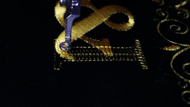 Machine embroidery on black velvet fabric with yellow thread. Embroidered ornaments and initials G and I. Close up. 4k video.