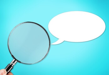 A blank speech bubble and hand holding a magnifying glass on a background.