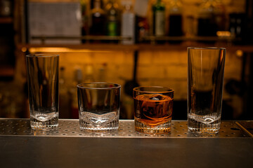 view of a group of empty and one full cocktail glasses on the bar counter.