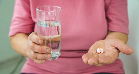 An old woman holds pills in her hands. Selective focus.
