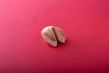 A whole traditional Chinese fortune cookie on a red background. Copy space view