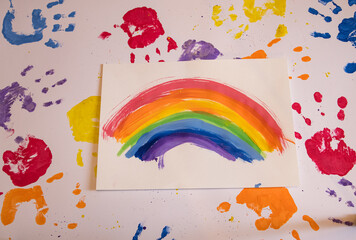 Colored children's hand prints and a rainbow pattern on a white background. Top view, flat position.