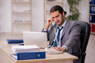 Naklejka premium Young male employee unhappy with excessive work in the office