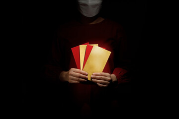 Asian woman wearing red dress showing red envelopes. Chinese new year Gong Xi Fa Cai. Ang pao, Hong bao with face mask