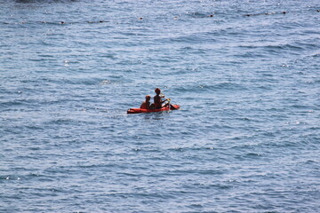 two people on a kayak are sailing on the sea on a hot summer day