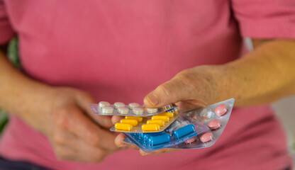 An old woman holds pills in her hands. Selective focus.