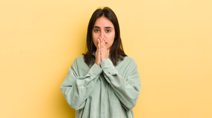young hispanic woman feeling worried, upset and scared, covering mouth with hands, looking anxious...