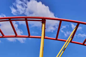 Part of a roller coaster. Background of blue sky and white clouds. Selective focus.