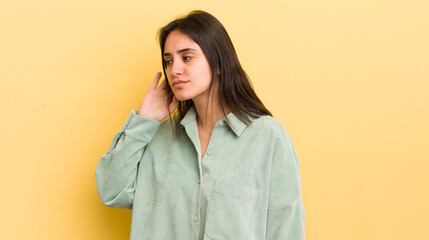 young hispanic woman looking serious and curious, listening, trying to hear a secret conversation...