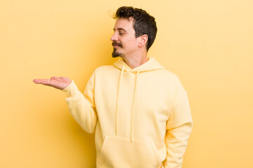 young hispanic man feeling happy and smiling casually, looking to an object or concept held on the...