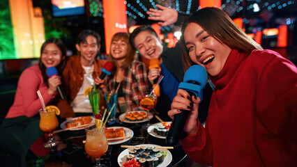 Singing into microphone and making selfie at karaoke party in club