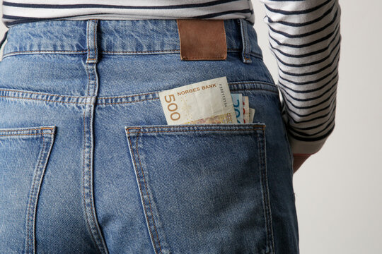Woman holding Norwegian krone banknotes in pocket of her jeans