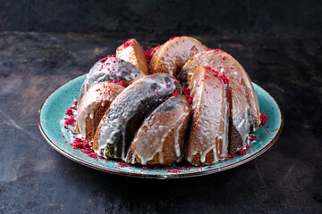 Traditional exotically bundt marble cocoa chocolate cake with icing sugar glaze and freeze dry raspberry topping served as close-up on a Nordic design plate with copy space