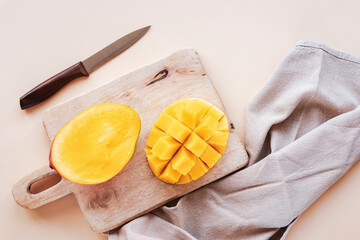 Halves of mango on a cutting board on beige backgrownd. Top view, flat lay