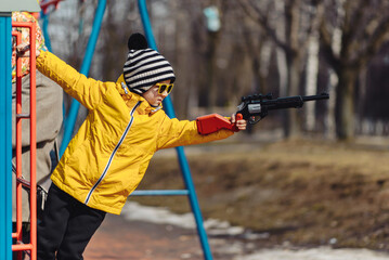 a boy on the playground takes aim with a toy gun