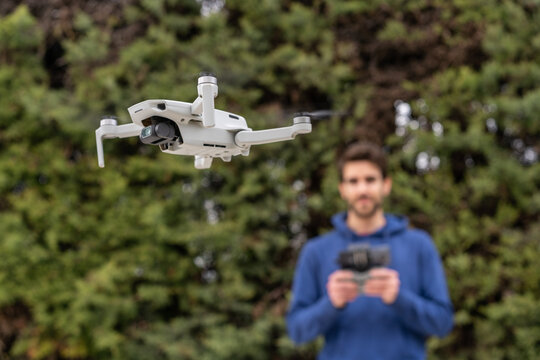 Young man controlling a flying drone outdoors in the park