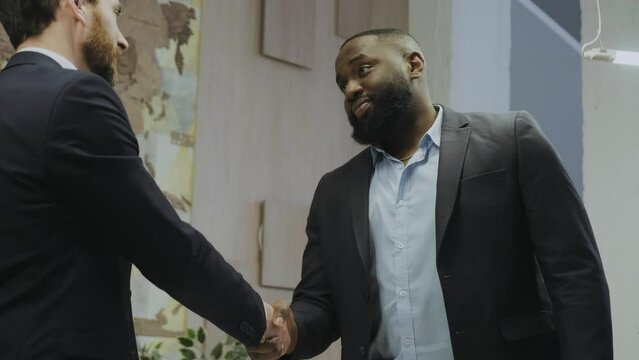 Greeting with handshake with serious face. Interracial meeting. Interracial handshake.