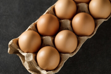 Whole chicken eggs in tray on dark background, selective focus.
