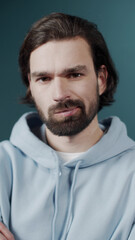 Isolated Dark-haired guy confused feels doubt while makes choice, dressed in casual hoodie