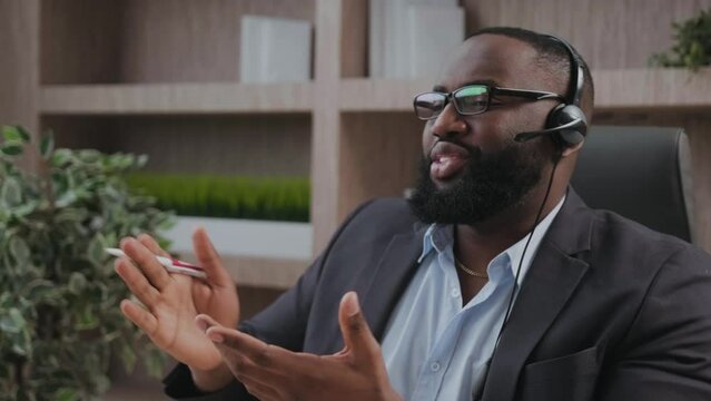 Representive African American practitioner leads online training wearing a suit and headset, active gestures and explanations