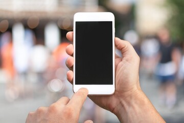 Human hand holding phone with blank screen and cityscape blur background