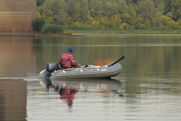 Fishing. A man on a rubber boat is fishing on the river in autumn.