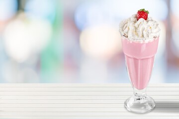 A glass of healthy strawberry smoothie with whipping cream on the desk