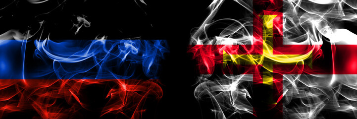 Donetsk People's Republic vs United Kingdom, Great Britain, British, Guernsey  flag. Smoke flags placed side by side isolated on black background.