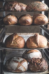 Foto op Plexiglas Vers gebakken zuurdesembrood op een plank © Maite Paternain