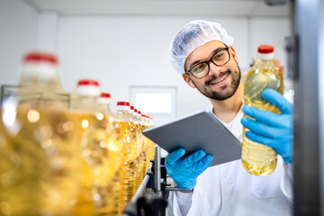 Food factory worker or technologist in white lab coat and hairnet standing by automated production...