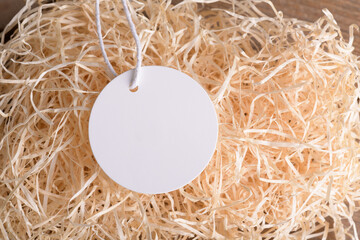 Round white tag mockup on a natural straw material for packing, close up. Label product mockup copy...