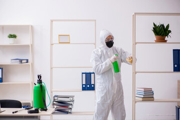 Young male contractor disinfecting office during pandemic