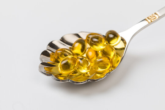 Close up of  oil filled capsules suitable for: fish oil, omega 3, omega 6, omega 9,  vitamin A, vitamin D, vitamin D3, vitamin E with a spoon - Image