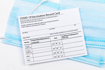 Obraz premium Coronavirus vaccination record card. Protective mask divided into two parts. Concept of defeating Covid-19 - Image
