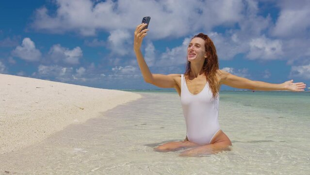 Beautiful woman at sea with a phone. Woman on the beach takes pictures of herself on a video camera. Blogger.