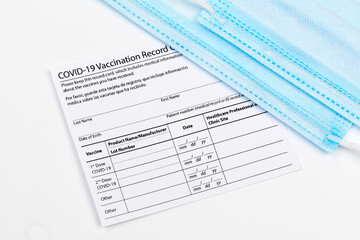 Obraz premium Coronavirus vaccination record card. Protective mask divided into two parts. Concept of defeating Covid-19 - Image
