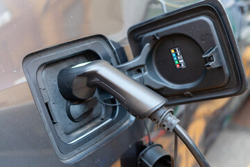 A cable is recharging an electric car at the charging station