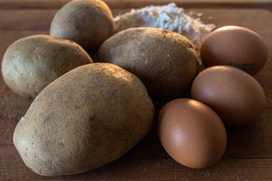potatoes, flour and eggs and on a wooden cutting board. ingredients for homemade pasta: gnocchi.