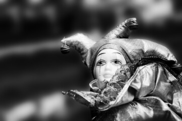 Vintage sad clown puppet against blurred background. Black white historic photo